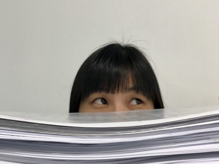 Woman looks over overwhelming paperwork.