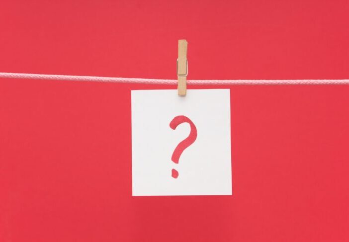 Red question mark on white paper hanging from a line