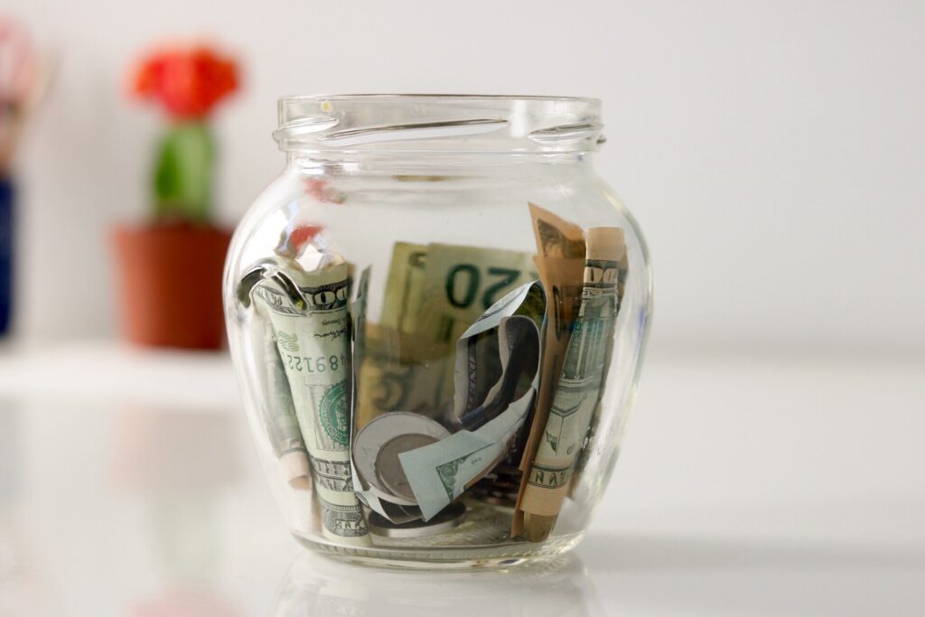 money jar with dollar bills sitting on table