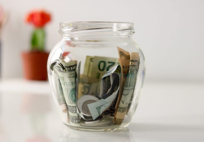 money jar with dollar bills sitting on table