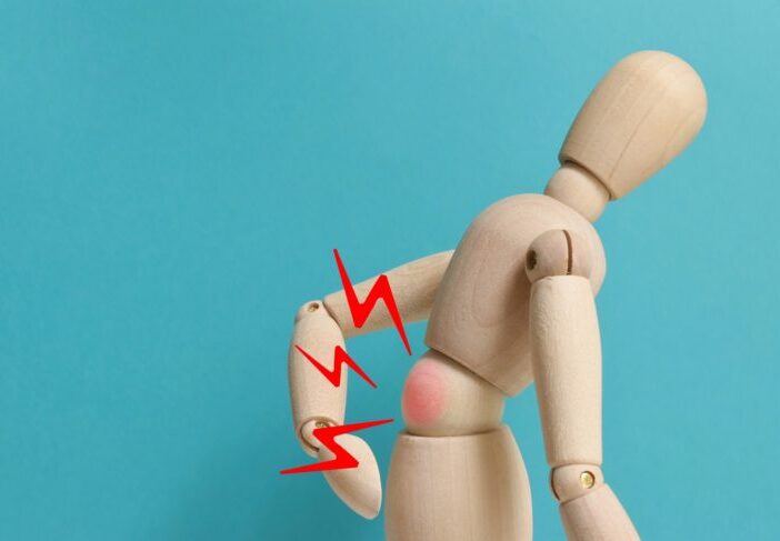 Wooden man on blue background with lower back pain