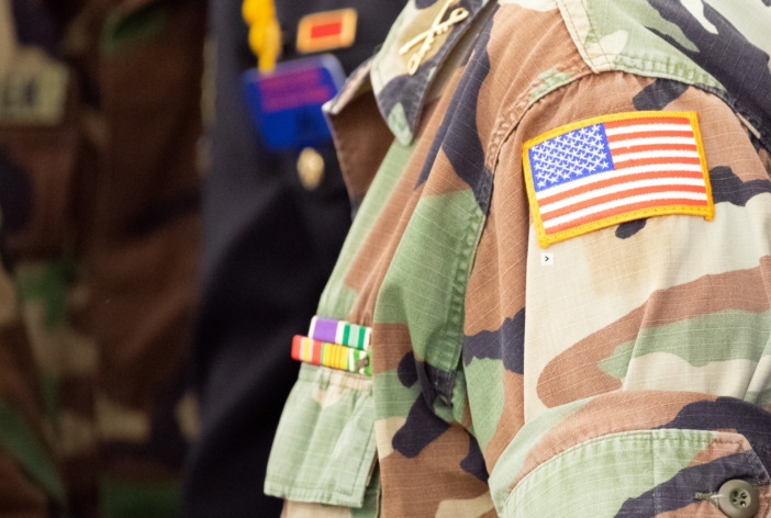 Veteran in an army uniform with an american flag.