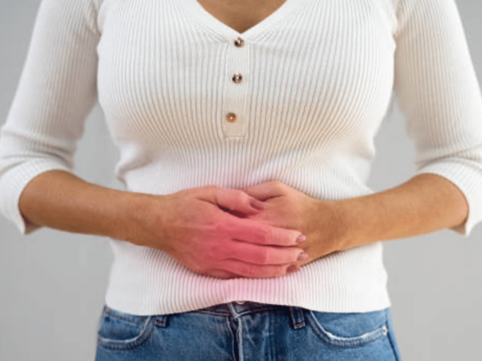 A person wearing a white long-sleeve shirt and jeans can be seen holding his or her hands over their upper abdominal area. There is a red glow over the individual's hands to indicate that the individual is experiencing pain here.