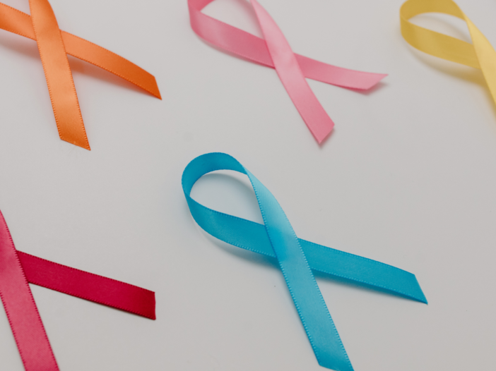 Bright colored ribbons on a white background signify cancer survivors.