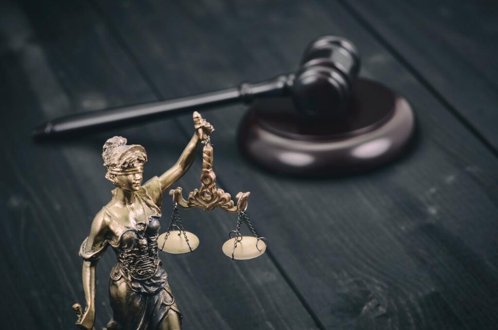 Statuette of Scales of Justice on desk with gavel in blurred background