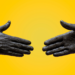 two hands shaking on a yellow background
