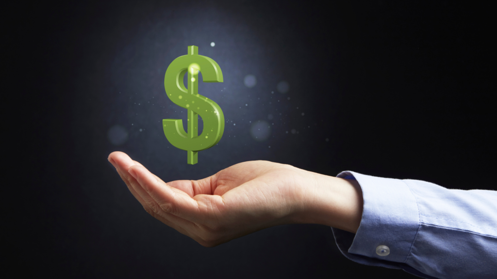 A Caucasian business person's hand, visible from the elbow down in a light blue business shirt cups their hand. A great dollar sign is floating above the hand.