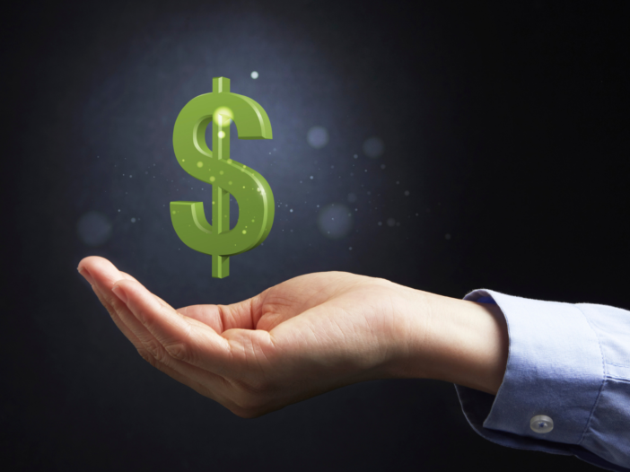 A Caucasian business person's hand, visible from the elbow down in a light blue business shirt cups their hand. A great dollar sign is floating above the hand.