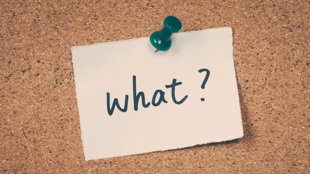 a post-it note with 'what' written on it and pinned to a cork board