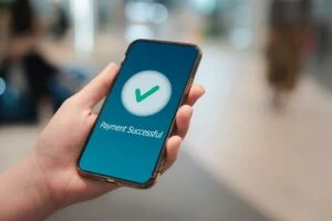 Hand holding a phone with 'payment successful' icon. Title of blog post is "How Much Does SSDI Pay in North Carolina? (Winston-Salem Guide)