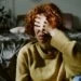 Woman sitting in a dark bedroom with her face in her hands. This is the header image for the blog post titled - "Can Anxiety or Depression Qualify for Disability?"