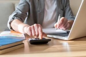 Picture of a man at a computer with a calculator making calculations. This image is the header image for a blog post titled - What Are Work Credits for Social Security Disability in North Carolina?