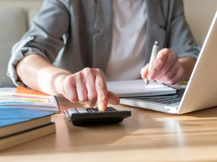Picture of a man at a computer with a calculator making calculations. This image is the header image for a blog post titled - What Are Work Credits for Social Security Disability in North Carolina?