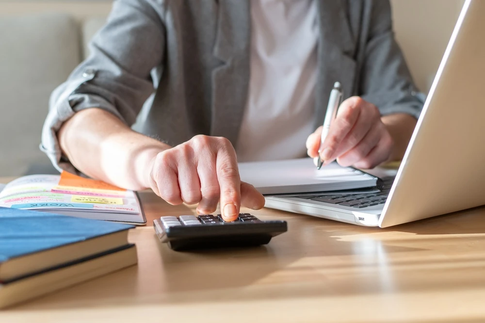 Picture of a man at a computer with a calculator making calculations. This image is the header image for a blog post titled - What Are Work Credits for Social Security Disability in North Carolina?