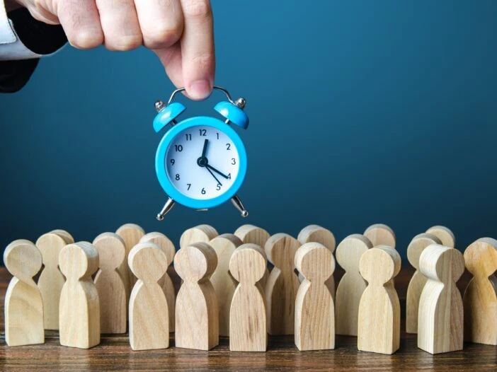 A,Businessman,Is,Holding,An,Alarm,Clock,Over,A,Crowd in this image that accompanies the blog post about Trial Work Periods and Social Security Disability