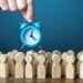A,Businessman,Is,Holding,An,Alarm,Clock,Over,A,Crowd in this image that accompanies the blog post about Trial Work Periods and Social Security Disability